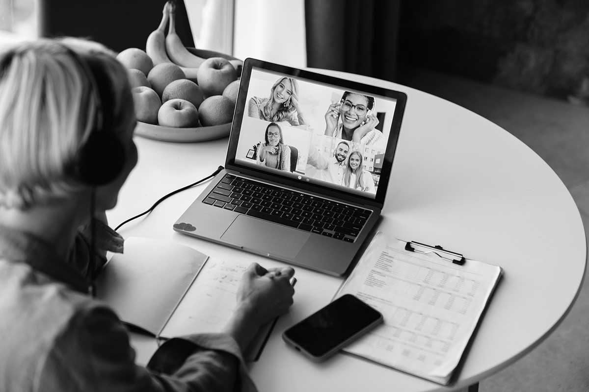 Videokonferanse med kolleger på laptop, notater på bordet.