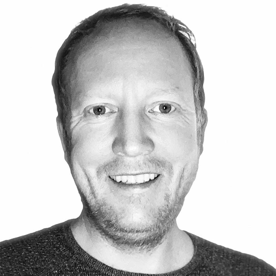 Smilende mann med skjegg mot hvit bakgrunn